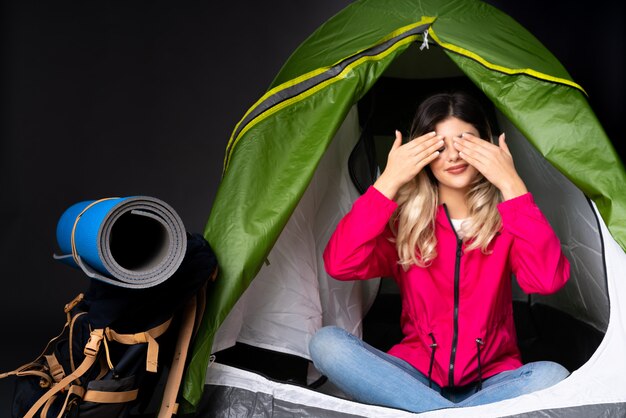 Menina adolescente dentro de uma barraca de acampamento verde