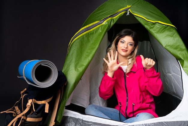 Menina adolescente dentro de uma barraca de acampamento verde