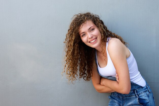 Menina adolescente despreocupada feliz, inclinando-se com os braços cruzados