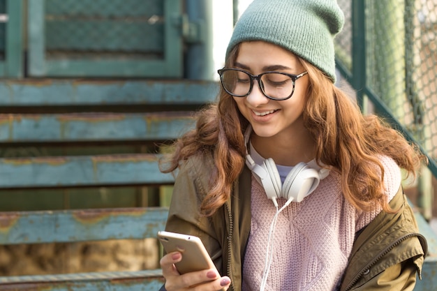 Menina adolescente elegante escreve uma mensagem de texto no smartphone.