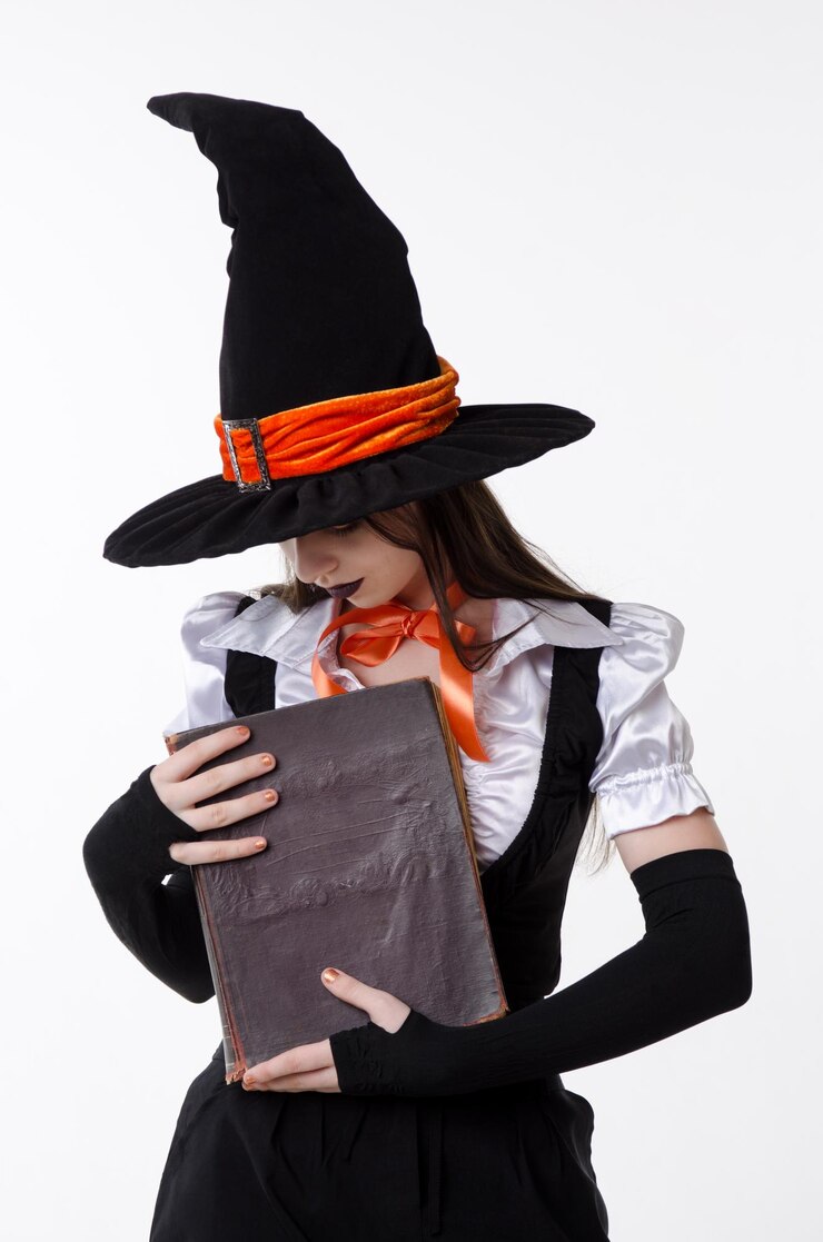 Foto menina adolescente em fantasia de bruxa de halloween e chapéu preto segurando o livro retrato de estúdio em fundo branco