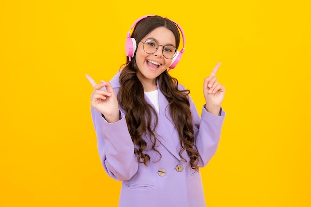 Menina adolescente em fones de ouvido ouve música Acessório de dispositivo de fone de ouvido sem fio Criança gosta de música em fones de ouvido em fundo amarelo