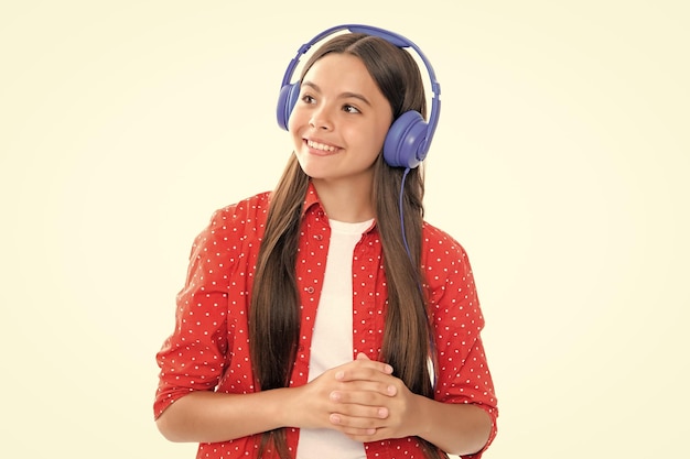 Menina adolescente em fones de ouvido ouve música Acessório de dispositivo de fone de ouvido sem fio Criança gosta de música em fones de ouvido em fundo branco Retrato de menina adolescente sorridente feliz