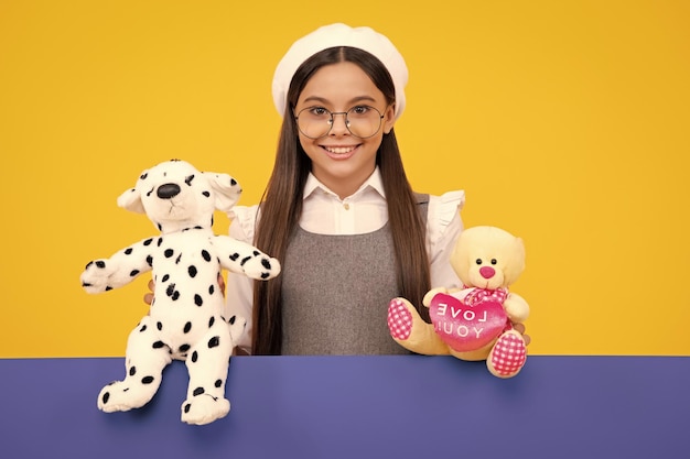 Menina adolescente em roupas casuais segurando o brinquedo de pelúcia isolado no fundo amarelo infância feliz Rosto feliz emoções positivas e sorridentes da menina adolescente