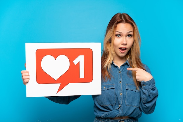 Foto menina adolescente em um fundo azul isolado segurando um cartaz com o ícone 