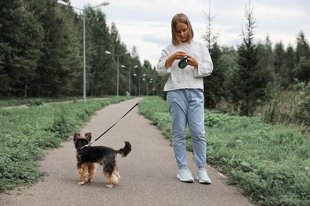 Menina adolescente em um passeio no parque de verão com seu animal de estimação Yorkshire terrier. Criança passeando com um cachorro