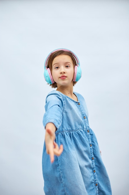 Menina adolescente em vestido jeans casual ouvindo música em fones de ouvido