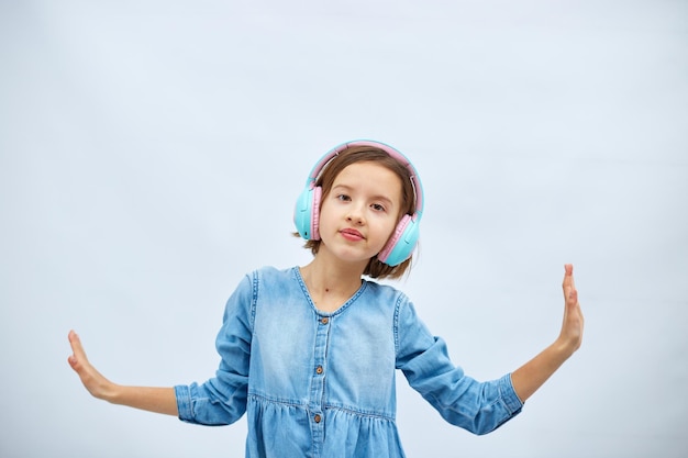 Menina adolescente em vestido jeans casual ouvindo música em fones de ouvido