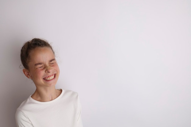 Menina adolescente emocional na camisa branca 11 12 anos de idade em um fundo branco isolado Retrato de estúdio infantil Coloque o texto para copiar o espaço para a inscrição de publicidade de produtos infantis