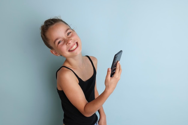 Menina adolescente emocional na camisa rosa 11 12 anos de idade em um fundo azul isolado com um tablet nas mãos Retrato de estúdio infantil 39 Coloque o texto para copiar o local para a inscrição