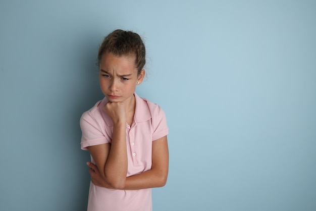 Menina adolescente emocional na camisa rosa 11 12 anos de idade em um fundo azul isolado Retrato de estúdio infantil Coloque o texto para copiar o espaço para a legenda de publicidade de produtos infantis