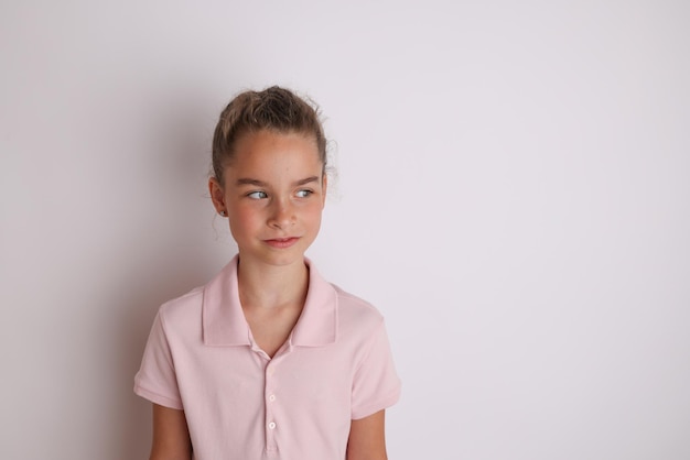 Menina adolescente emocional na camisa rosa 11 12 anos de idade em um fundo branco isolado Retrato de estúdio infantil Coloque o texto para copiar o espaço para a inscrição de publicidade de produtos infantis