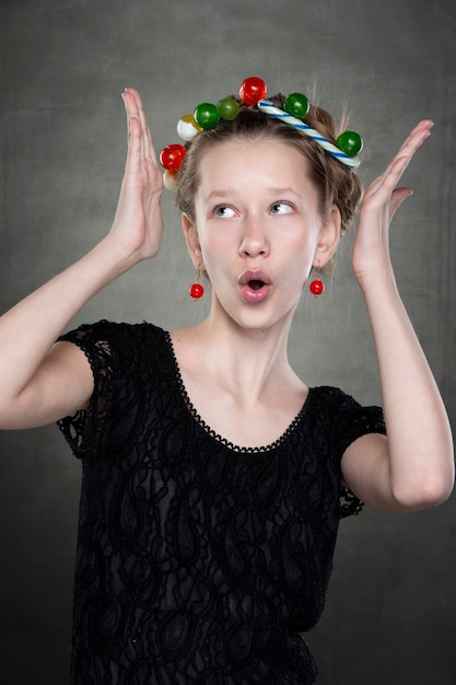 Menina adolescente engraçada com uma coroa de doces na cabeça, brincando na frente da câmera.