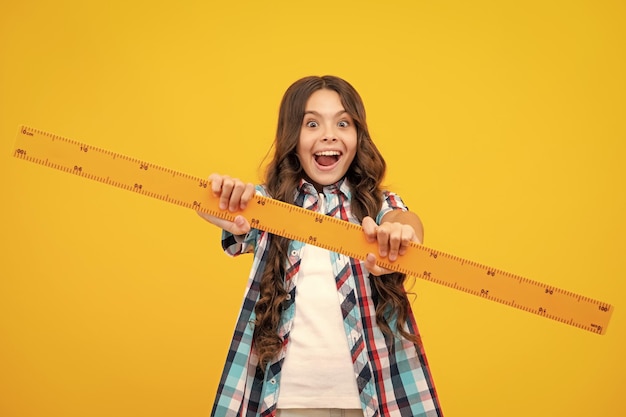 Menina adolescente espantada Menina da escola adolescente estuda matemática ou aula de geometria mede o tamanho Régua matemática para medir Expressão animada alegre e feliz