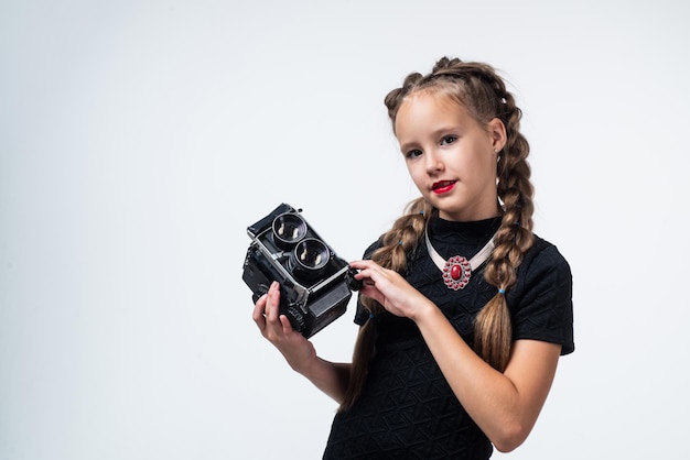 Menina adolescente fazendo foto câmera retrô feliz criança de infância tem fotografia de aparência elegante na vida moderna criança com câmera fotográfica antiquada isolada no espaço de cópia de tecnologia vintage branco