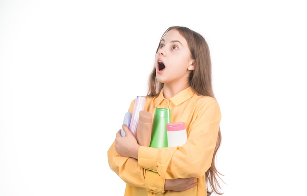 Menina adolescente feliz apresentando xampu ou frasco de condicionador de cabelo isolado em branco nutritivo