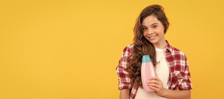 Foto menina adolescente feliz com cabelo longo encaracolado segura frasco de xampu cosmético banner do cabeçalho do pôster do estúdio de cuidados com o cabelo de menina com espaço para cópia