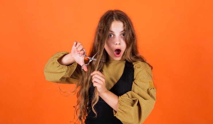 Foto menina adolescente feliz corta o cabelo com tesoura de cabeleireiro