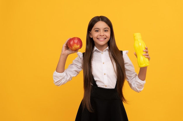 Menina adolescente feliz da escola de uniforme segurar maçã e garrafa de água, saúde.