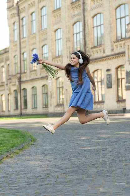 Menina adolescente feliz em fones de ouvido menina corre ao ar livre menina despreocupada correndo sente felicidade