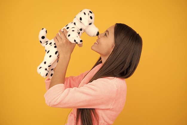 Menina adolescente feliz em roupão de banho em casa com amor de brinquedo