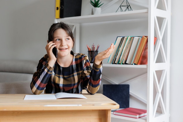 Menina adolescente feliz falando em seu celular durante uma aula