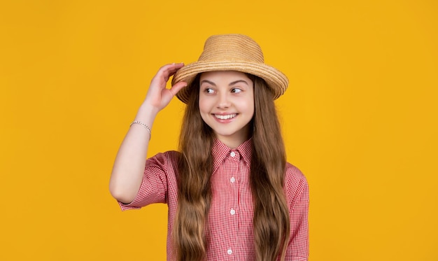 Menina adolescente feliz no chapéu de palha no fundo amarelo