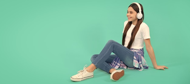 Menina adolescente feliz ouve música em fones de ouvido sem fio Retrato de criança com cartaz horizontal de fones de ouvido Menina ouvindo banner de música com espaço de cópia