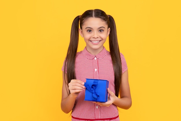 Menina adolescente feliz segura caixa de presente no dia de boxe de fundo amarelo