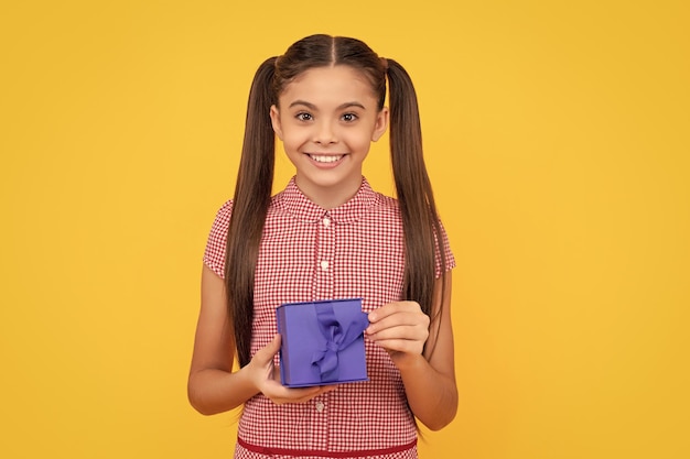 Foto menina adolescente feliz segura caixa de presente no dia de boxe de fundo amarelo