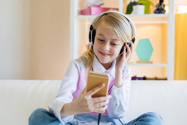 Menina adolescente feliz usando smartphone e fones de ouvido ouvindo música