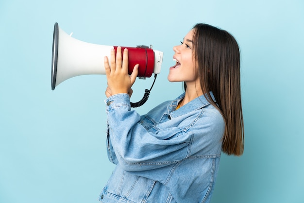 Menina adolescente isolada em amarelo gritando em um megafone para anunciar algo