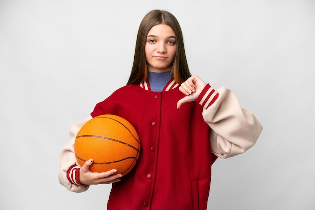 Menina adolescente jogando basquete sobre fundo branco isolado, mostrando o polegar para baixo com expressão negativa