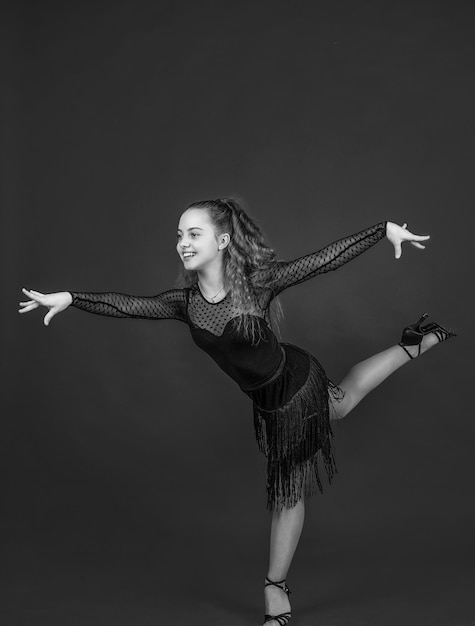 Menina adolescente linda dançarina de salão usa vestido preto em pose de dança dançando