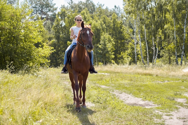 Menina adolescente, montando um cavalo marrom, passeios a cavalo para as pessoas no parque