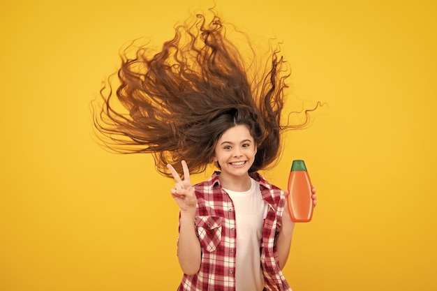 Menina adolescente mostrando condicionadores de xampu de garrafa ou gel de banho Produto cosmético de cabelo Garrafa para publicidade mock up cópia espaço Adolescente feliz emoções positivas e sorridentes de adolescente