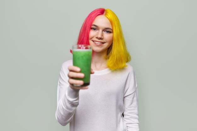 Menina adolescente na moda com copo de smoothies verdes frescos