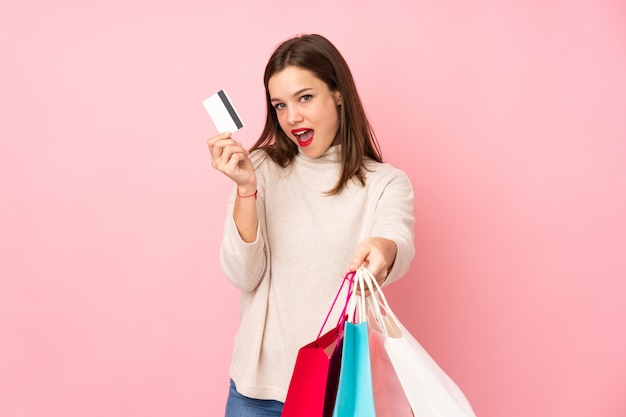 Menina adolescente na rosa segurando sacolas de compras e cartão de crédito