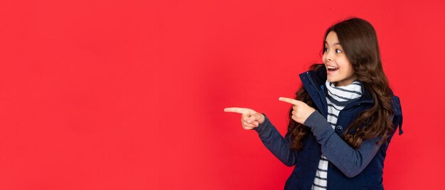 Menina adolescente no retrato de fundo vermelho de criança vestindo roupas quentes expressa emoção positiva