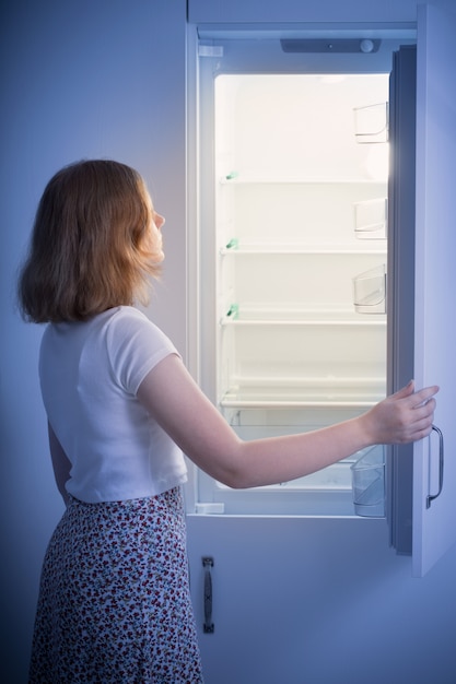 Foto menina adolescente pela geladeira vazia