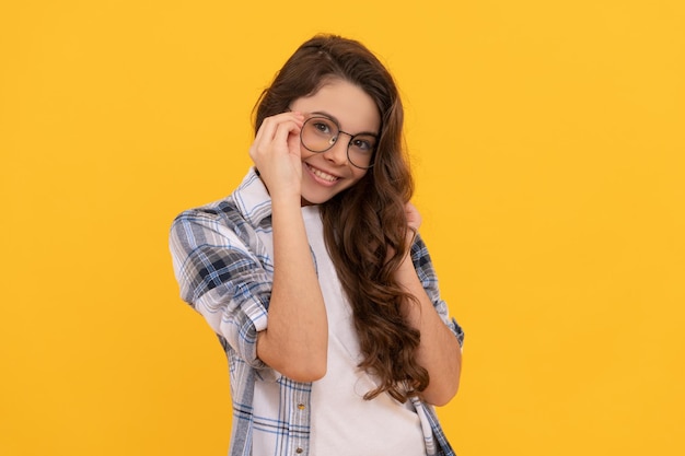 Menina adolescente positiva em camisa quadriculada e óculos em fundo amarelo