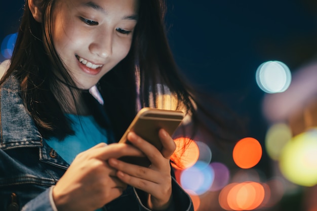 Menina adolescente que usa o telefone móvel para conversar e enviar a mensagem.