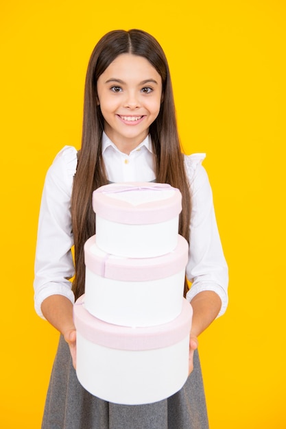 Menina adolescente segurando a caixa de presente isolada em fundo amarelo Presente para aniversário de crianças