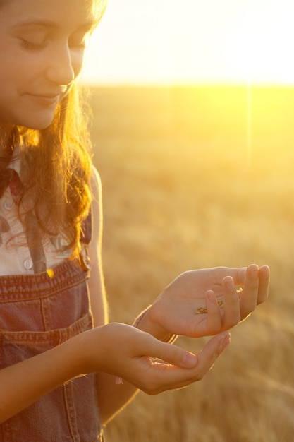 Menina adolescente segurando grãos de trigo na hora do pôr do sol