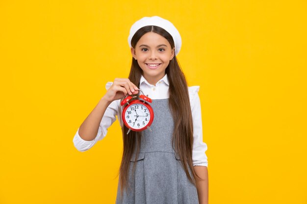 Menina adolescente segurando o relógio sobre fundo amarelo Cronograma diário de manhã cedo Criança verificando o tempo não se atrase Garoto pontual com alarme Hora do prazo Garota feliz rosto positivo e sorridente