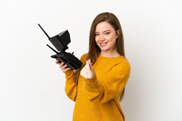 Menina adolescente segurando um controle remoto de drone sobre um fundo branco isolado fazendo gesto de dinheiro