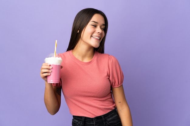 Menina adolescente segurando um milkshake de morango olhando de lado