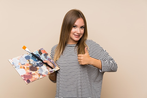 Foto menina adolescente segurando uma paleta sobre parede isolada, dando um polegar para cima gesto