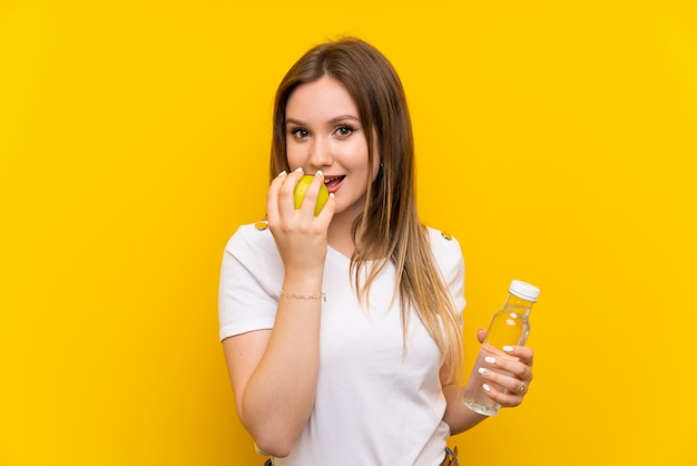 Foto menina adolescente, sobre, parede amarela, com, um, maçã, e, um, garrafa água