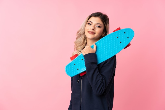 Foto menina adolescente sobre rosa isolado com skate